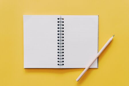 Notebook and pencil on yellow texture background.の写真素材