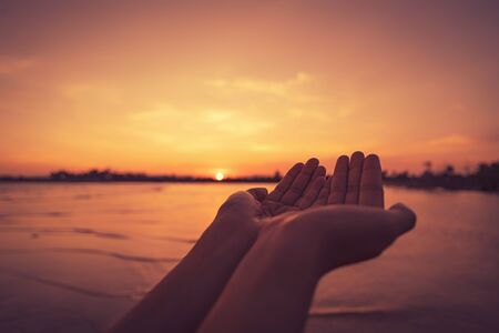 Woman open hand up on tropical sunset background. Vintage tone color style.の写真素材