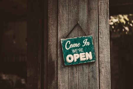 Open sign broad hanging on wood door front of cafe. Business service and food concept. Vintage tone...