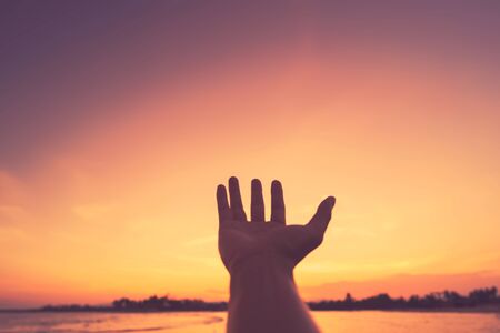 Man open hand up on tropical sunset background. Vintage tone color style.