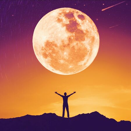 Man raise hand up on top of mountain with sunset sky and full moon star abstract background. Copy...