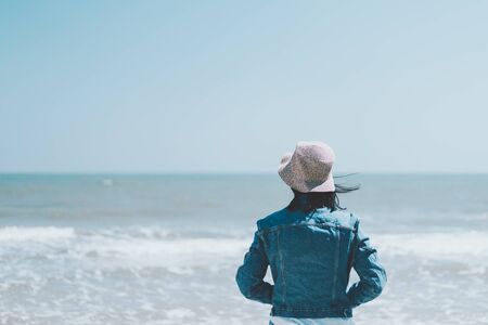 Freedom feel good and travel adventure concept. Copy space of woman stand looking view with blue sky and wind wave on beach background. Vintage tone filter effect color style.の写真素材