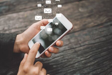 Woman hand using smart phone at coffee shop with email icon flying abstract background. Technology business and freelance concept. Vintage tone filter effect color style.の写真素材