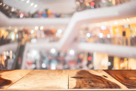Wooden tabletop on blur people walking in shopping center mall abstract background. Copy space of business travel concept. Retro tone filter color style.の写真素材