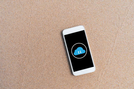 Smart phone on tropical sand beach with cloud icon abstract background. Technology business and...