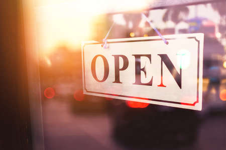 Open sign broad hanging on wood door front of cafe. Business service and food concept. Vintage tone filter effect color style.の写真素材