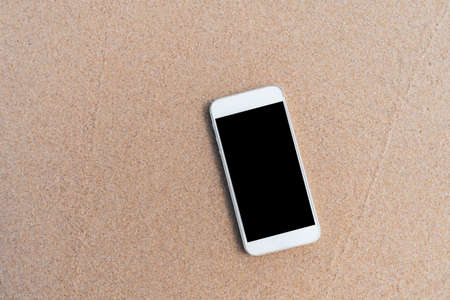 Smart phone on tropical sand beach texture background. Black copy space of technology business and travel nature concept.の写真素材