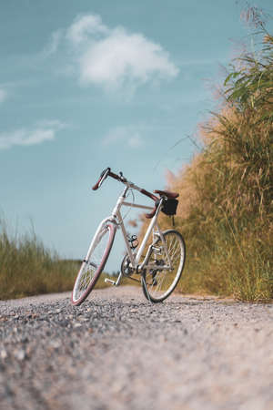 Vintage bicycle on country road and field with blue sky and white cloud abstract background.の写真素材