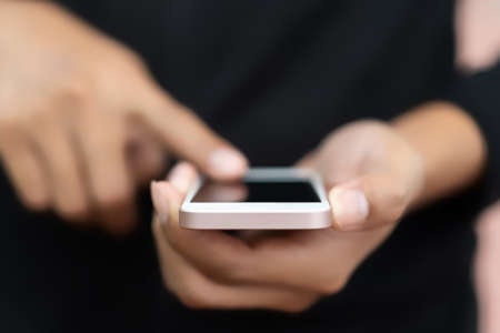 Close up man hand hold using smart phone on outdoor park street background. Copy space of technology...