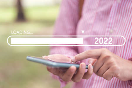 Close up woman hand hold using smart phone with loading bar new year 2022 on outdoor park street...
