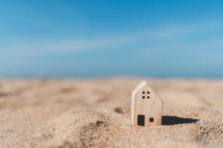 Small home model on sunset beach sand texture background. Copy space of family lifestyle and business real estate concept. Vintage tone filter effect color style.の写真素材
