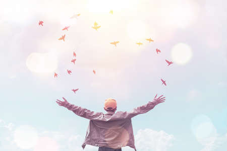 Man raise hands on blue sky  and birds flying with colorful bokeh light abstract background. Freedom...