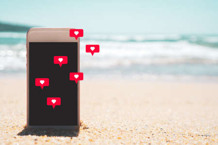 Smart phone on tropical beach with heart chat ion flying abstract background. Summer holiday and...