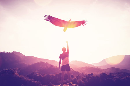Man raise hand up on top of mountain and sunset sky with eagle birds fly abstract background. Copy space freedom travel adventure and business victory concept. Vintage tone filter effect color style.の写真素材