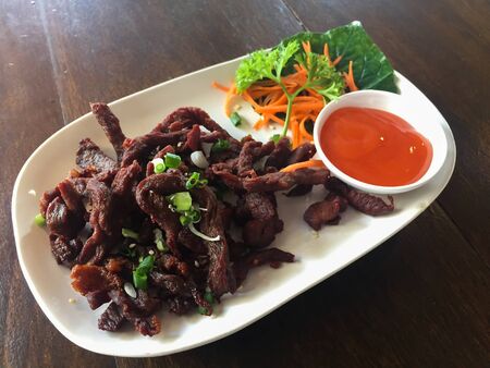 Dry salami sausage sliced on an wooden board and covered with spices.の写真素材