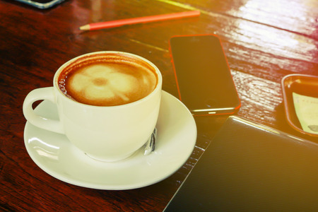 Laptop at cafe shop coffee cup and mobile phone on table.の写真素材
