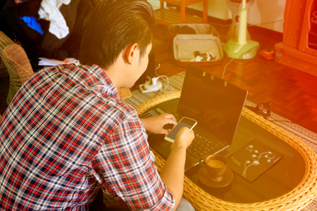 Man using smartphone with laptop, Nomad worker concept.の写真素材