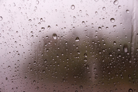 Textures of water droplets of rain flow down the windowpane. Rain drop on the car glass background,...