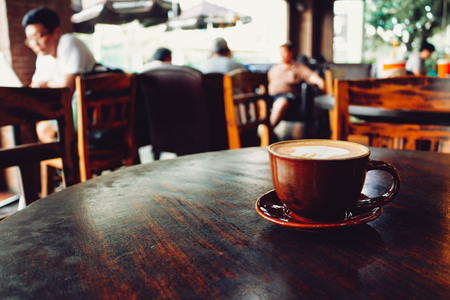Latte coffee cup on wooden table in cafeの写真素材