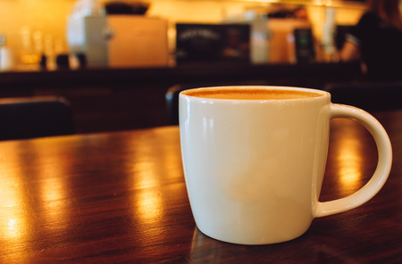Latte coffee cup on wooden table in cafeの写真素材