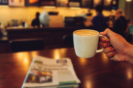 Male hands holding cup of coffee on table in cafeの写真素材