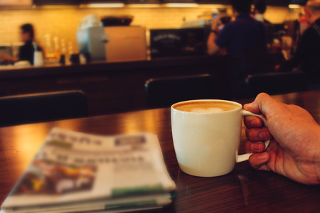 Male hands holding cup of coffee on table in cafeの写真素材