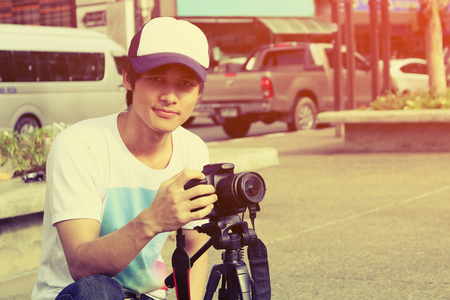 Handsome thai man photographer to pay close attention to take a photo, Traveler Lifestyle Concept, vintage style.の写真素材