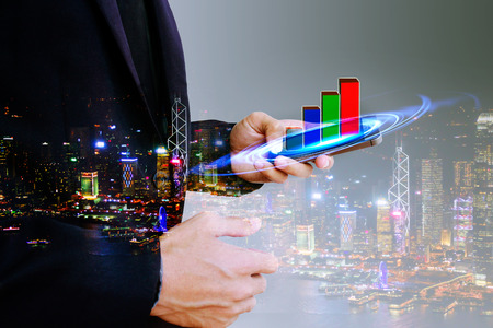 Double exposure of Businessman looking a prosperous economy graph up , on modern mobile phoneの写真素材