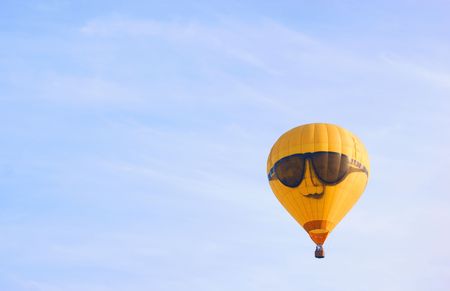 A yellow hot-air balloon against a blue skyの写真素材