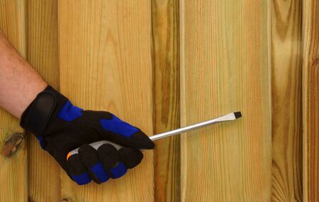Hand with screwdriver, agains wooden background