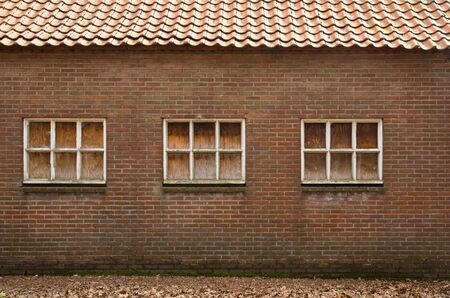 Old wall with windows, windows have been covered with wooden panelsの写真素材