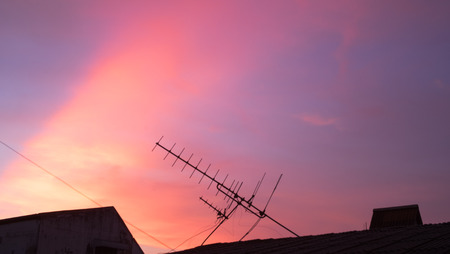 Sunset in violet, orange and blue sky with roof and antenna