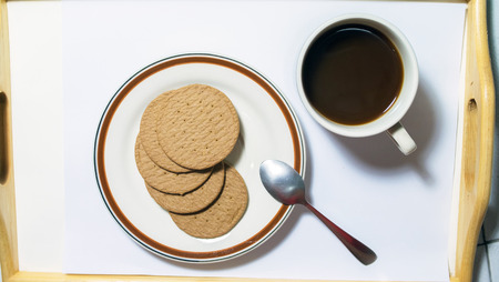 Brown biscuits in dish pairing with black coffees with teaspoonの写真素材