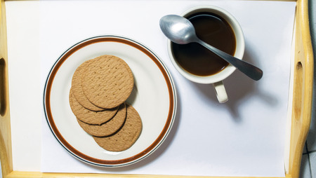 Brown biscuits in dish pairing with black coffees with teaspoonの写真素材