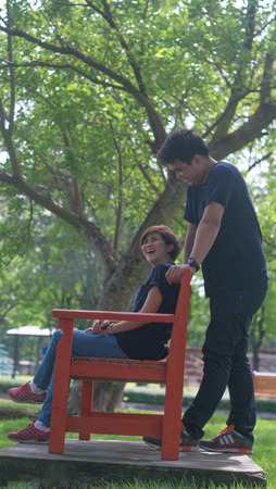 Girfriend sit and laughing for her boyfriend's joke in the chair in the garden for pre wedding shootingの写真素材