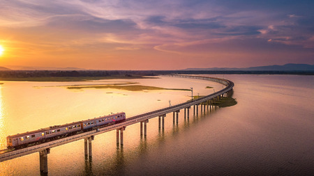 Aerial View The train is running on the bridge Over River Pa Sak Dam Lopburi Thailand and Beautiful sunsetの写真素材