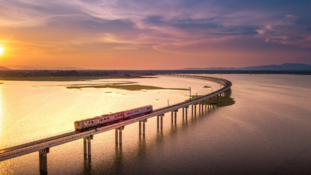Aerial View The train is running on the bridge Over River Pa Sak Dam Lopburi Thailand and Beautiful sunsetの写真素材
