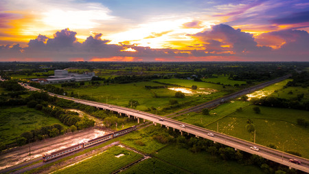 Aerial Photo Countryside Road Bridge Over Railway The train is running through the bridge and Golden Hour Sky Beautiful Landscape Drone Viewの写真素材
