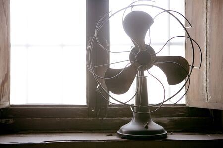 Antique vintage air fan in the window backlightの写真素材