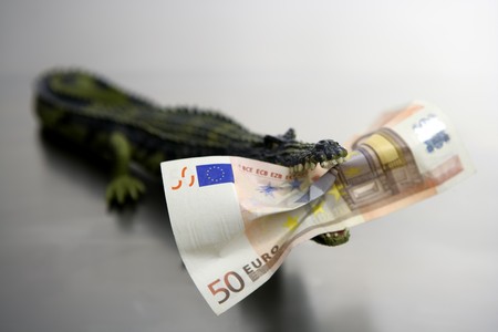 Toy plastic cocodrile, aligator with  fifty euro banknote  in its sharped theet jaws metaphorの写真素材