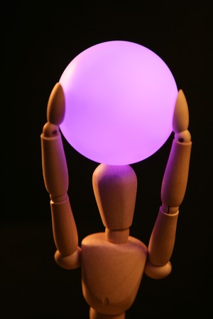 wooden mannequin holding a pink light ball over headの写真素材