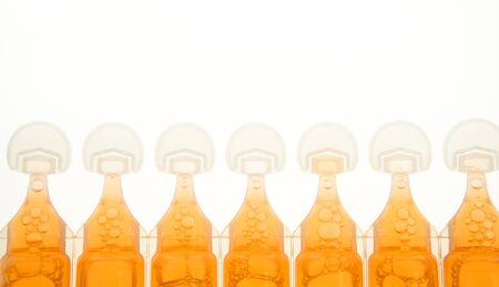 ampoule in plastic for liquid orange medicine, backlight, white background