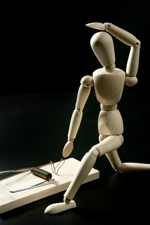 Wooden mannequin with mouse trap, over black backgroundの写真素材