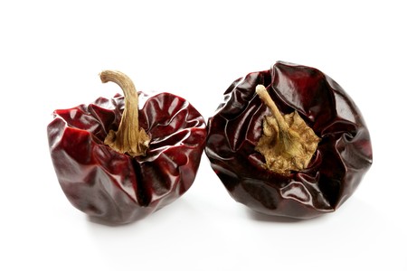 Two round Mediterranean dried dark red peppers over white at studio, isolatedの写真素材