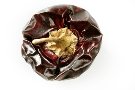 One round Mediterranean dried dark red peppers over white at studio, isolated