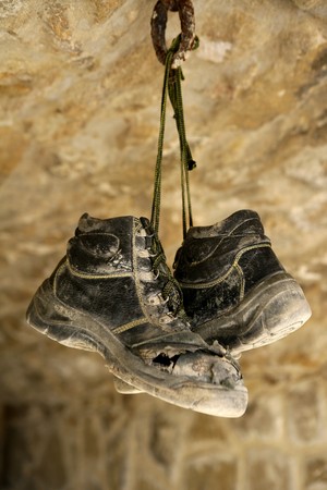 Construction worker left his aged old boots away, hunged on the rocksの写真素材