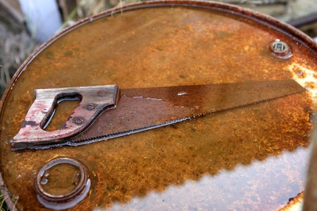 Rusted old saw tool over rusty orange backgroundの写真素材