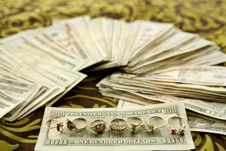 Dollar notes and gold rings over tablecloth, studio recreationの写真素材