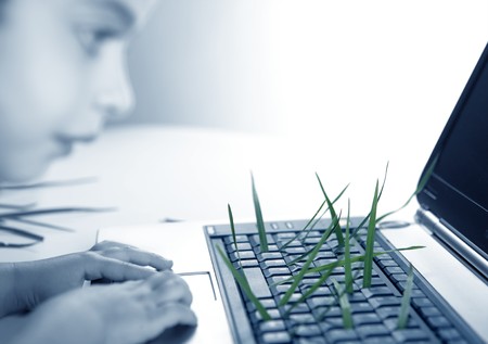 Grass growing from computer keyboard, ecology metaphor with girlの写真素材