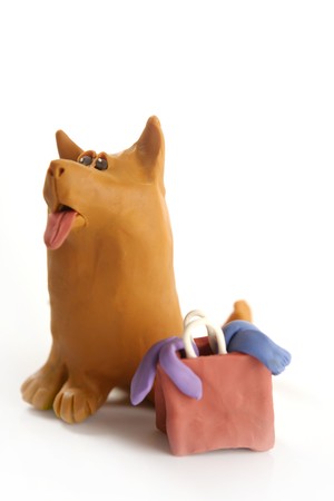 orange plasticine dog goes shopping with bag, isolated on whiteの写真素材